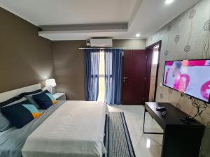 a bedroom with a bed and a flat screen tv at Lovely Guest House in Luanda in Luanda