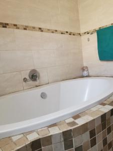 a white bath tub in a tiled bathroom at Sagewood Manor in Midrand