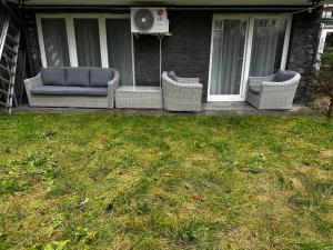 tres sillas de mimbre sentadas en el porche de una casa en Kompleks Apartament-Serwis, en Cracovia