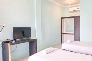 Cette chambre comprend 2 lits et une télévision sur une table. dans l'établissement Homestay Dalimo 2 Syariah RedPartner, à Payakumbuh