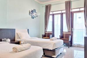 a room with two beds and chairs and windows at Homestay Dalimo 2 Syariah RedPartner in Payakumbuh