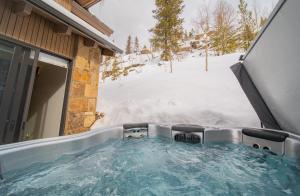 una bañera de hidromasaje en un patio cubierto de nieve en Wolf Rock Home 82 en Keystone
