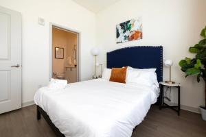 um quarto com uma grande cama branca e uma cabeceira azul em Modern Nulu 2BR CozySuites 04 em Louisville