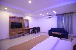 una camera con letto, TV e divano di Queen-C Inn a Mānantoddy