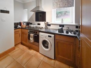 a kitchen with a washing machine and a sink at Station Cottage in Trinafour
