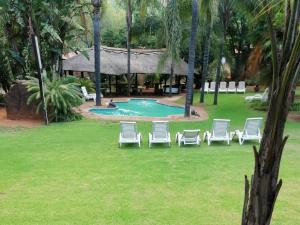 a group of lawn chairs and a swimming pool at Kettle Guest Lodge Rustenburg in Rustenburg