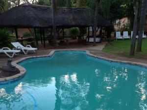 a swimming pool with a gazebo at Kettle Guest Lodge Rustenburg in Rustenburg