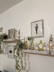 a shelf with gold vases and a picture on it at Orphea - Charming Studio Villeparisis - Proche gare / CDG / Parc des expositions in Villeparisis