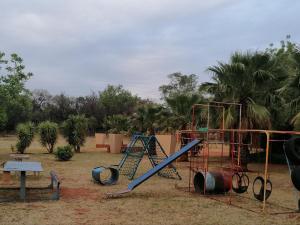 a playground with a slide and a swing set at Kettle Guest Lodge Rustenburg in Rustenburg