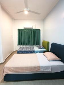 duas camas num quarto com uma cortina verde em Amuse Homestay at Kuala Kubu Bharu em Kuala Kubu Baharu