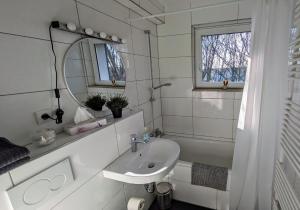 La salle de bains blanche est pourvue d'un lavabo et d'un miroir. dans l'établissement Schöne Wohnung Kerpen, à Kerpen