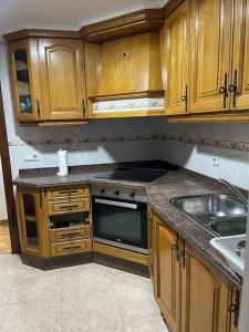 a kitchen with wooden cabinets and a sink at Piso completo en Calle Tibi in San Vicente del Raspeig +3 photos