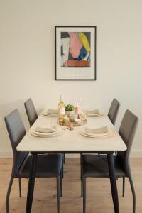 einen Esstisch mit Stühlen und ein Gemälde in der Unterkunft Luxury Apartment Cherrywood Dublin 18 in Dublin