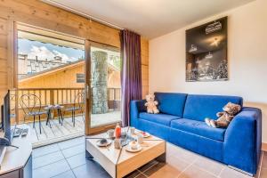 uma sala de estar com um sofá azul e uma varanda em Résidence Les Balcons EtoilÉs - 2 Pièces pour 4 Personnes 194157 em Champagny-en-Vanoise