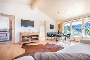 ein Wohnzimmer mit einem Tisch, Stühlen und einem TV in der Unterkunft Exklusives Design-Apartment & Sauna in Warngau