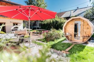 a large red umbrella in a garden with a wooden cabin at Exklusives Design-Apartment & Sauna in Warngau