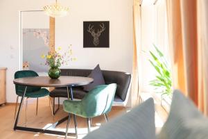 ein Esszimmer mit einem Tisch und grünen Stühlen in der Unterkunft Exklusives Design-Apartment & Sauna in Warngau