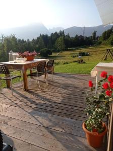 una terraza de madera con mesa, sillas y flores en Pedibosco Orange en Calalzo