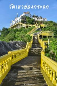 una scala gialla che conduce su una collina con un edificio di O-Bay Design Hotel Prachuap a Prachuap Khiri Khan
