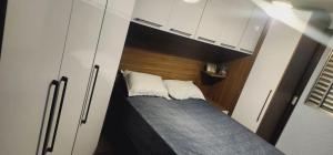 um pequeno quarto com uma cama e armários brancos em Apê perto Alphaville em Osasco