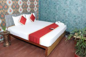 1 dormitorio con 1 cama con sábanas blancas y almohadas rojas en Hotel New Agarwal en Jhunjhunūn