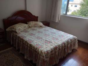 a bedroom with a bed with a quilt and a window at Apartamento in São Lourenço