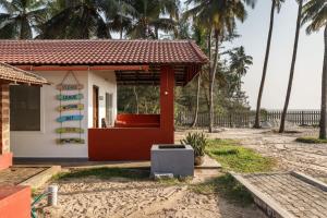 a small house on the beach with palm trees at Surfside Haven By JadeCaps 1BHK By Udupi Beach in Kōtatattu