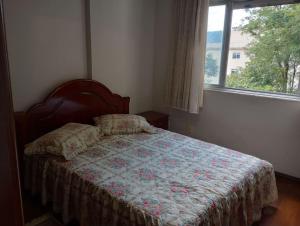 a bedroom with a bed with a quilt and a window at Apartamento no Centro de São Lourenço in São Lourenço