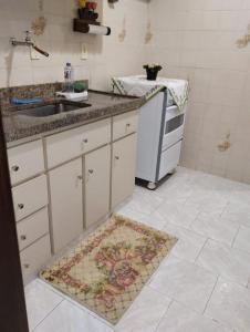 a kitchen with a sink and a rug on the floor at Apartamento in São Lourenço