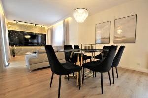 a dining room with a table and black chairs at Grand Royal Baltic Ustka - luksusowy Apartament 150 metrów od plaży, port, zielony taras, bezpłatny parking, top lokalizacja w centrum Ustki in Ustka