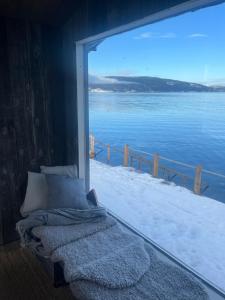 a bed in a room with a view of the water at Lykkja - Beautiful Waterfront House in Viggja