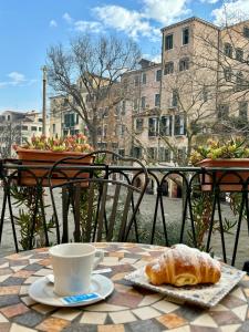 Locanda del Ghetto في البندقية: طاولة مع فنجان قهوة وكرواسون