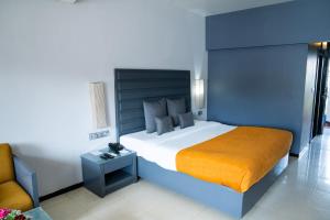 um quarto com uma cama grande e uma cadeira em Baywatch Resort, Colva Goa em Colvá
