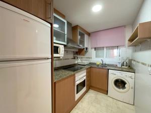 a kitchen with a white refrigerator and a dishwasher at Apartamentos Costamar 3000 in Torre de la Sal