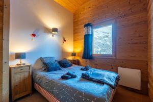 sypialnia z łóżkiem z niebieskimi prześcieradłami i oknem w obiekcie Cosymontagne - Le Chalet - 3Ch - 8 pers- Terrasse Sud, magnifique vue w mieście Clusaz