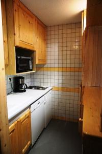 a small kitchen with wooden cabinets and a microwave at Résidence Rond Point I - Studio pour 4 Personnes 04 in Orcières