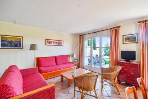 a living room with a red couch and a table at Les Maisons de Pont Royal en Provence - maeva Home - Maison climatisée pour 8 Personnes avec jardin privatif et terrasse MAE-2283 in Mallemort