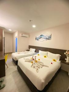 a hotel room with two beds with flowers on them at Well Hotel By Maco at Legoland in Gelang Patah