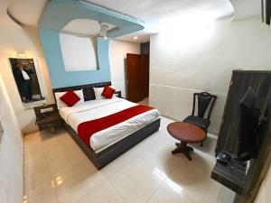 1 dormitorio con 1 cama, TV y silla en Hotel Sadbhav en Ahmedabad