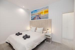 a white bedroom with a large white bed and a desk at Apartamentos turísticos Playa Marinsa in Torre del Mar