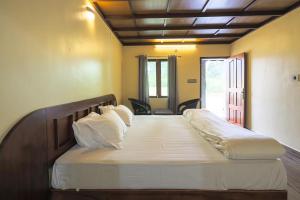 1 dormitorio con 1 cama grande con sábanas y almohadas blancas en Vineyard Homestay en Santhanpara