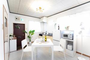 SuizawaにあるSuzuka Smile Roomの白いテーブルと椅子のある白いキッチン