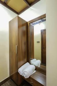 y baño con 2 espejos y toallas blancas. en Vineyard Homestay en Santhanpara