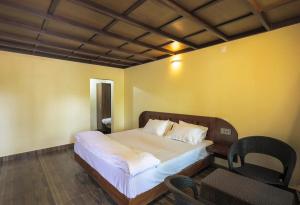 1 dormitorio con 1 cama y 2 sillas en Vineyard Homestay en Santhanpara