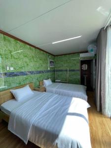 a bedroom with two beds and a green wall at Motel Ngọc Hiền in Pleiku