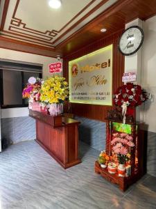 a lobby with a clock and flowers on a wall at Motel Ngọc Hiền in Pleiku