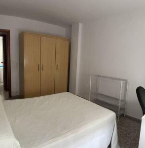 a bedroom with a bed and a wooden cabinet at Piso completo en Calle La Huerta in San Vicente del Raspeig