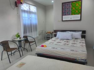 Schlafzimmer mit einem Bett, einem Tisch und Stühlen in der Unterkunft Homestay Erna Tanjong Tinggi in Pasarbaru