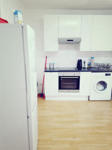 cocina con armarios blancos, lavadora y secadora en Double Room Close To Headingley Stadium Leeds, en Leeds