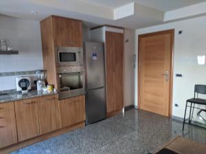 a kitchen with a stainless steel refrigerator and wooden cabinets at DUPLEX Maravilla en la Catedral in Jaca